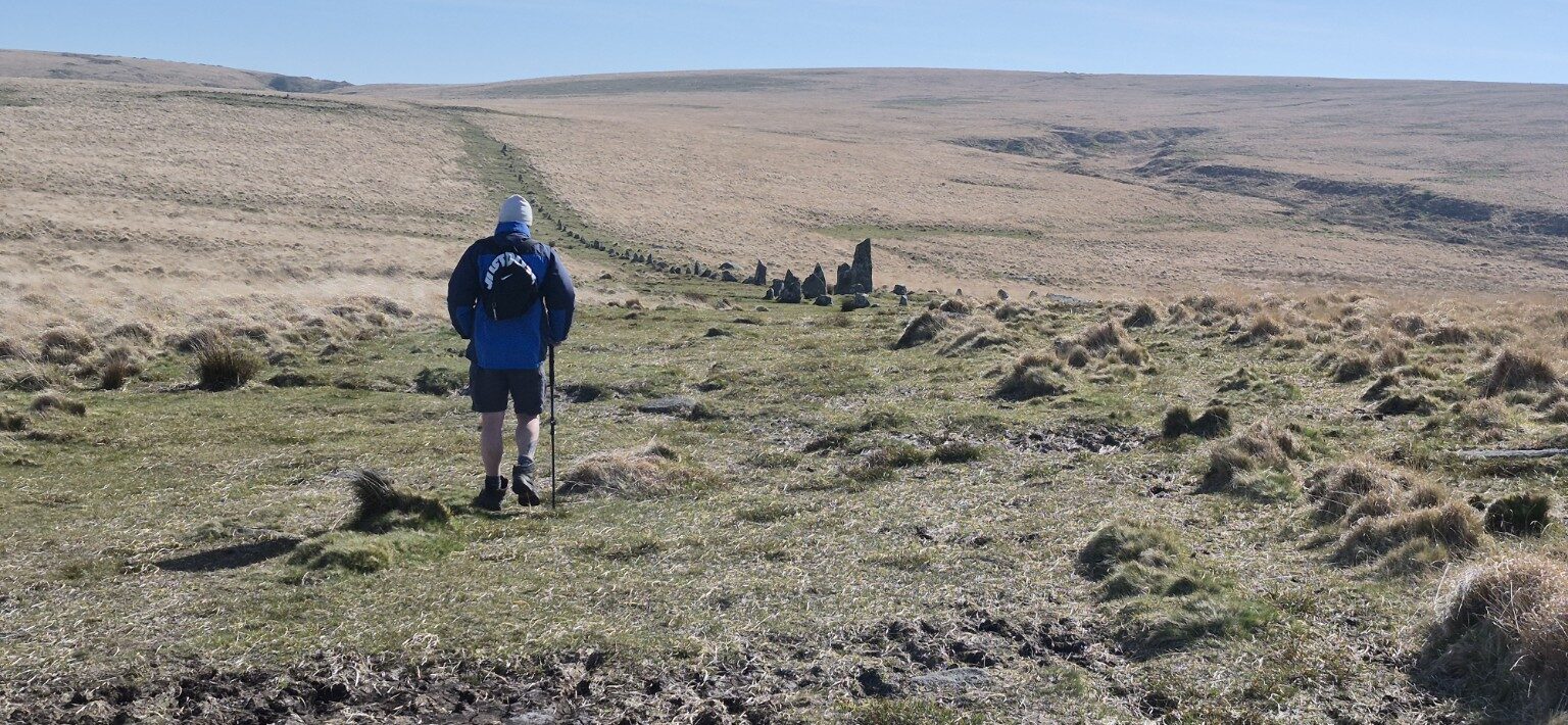 A hiker walking beside the ancient Hingston Hill Stone Row
